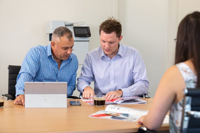 Sales staff sitting at a desk having a meeting with someone